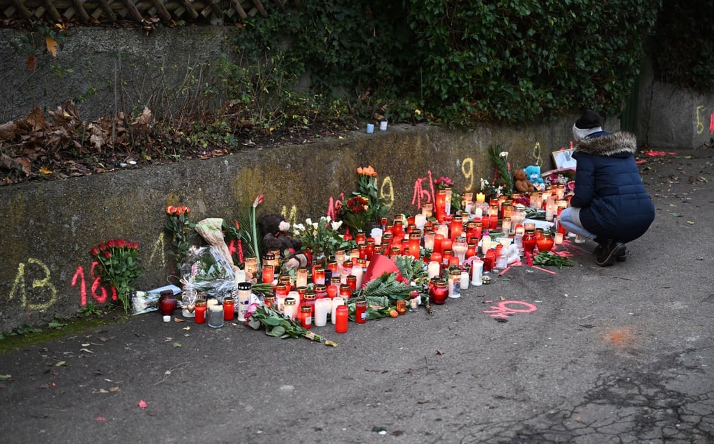 Eine Frau zündet am Tatort eines Messerangriffs eine Kerze an. Am Tag zuvor sind zwei Mädchen von einem Mann angegriffen worden, eine 14-Jährige erlag ihren schweren Verletzungen.