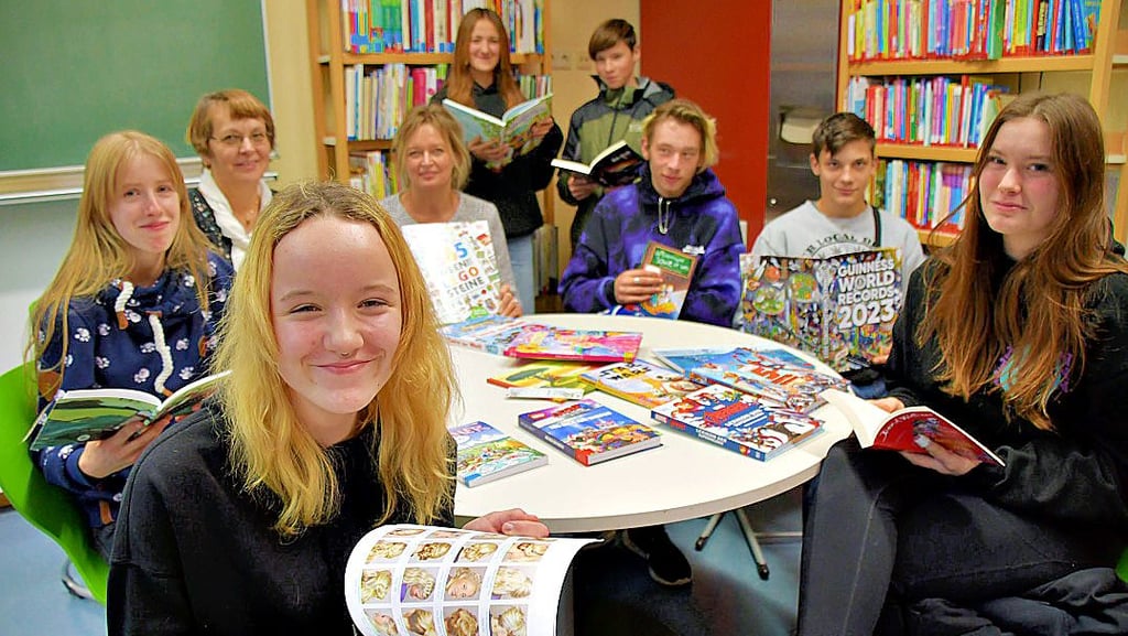 Angelique (vorn; v.l.), Emily, Bibliothekarin Herta Springborn, Schulleiterin Ariane Zessin-Petzschull, Lucia, Taylor, Jan-Luca, Jonas und Shanya stöbern in den neuen Büchern in der Bibliothek der Johann-Heinrich-Pestalozzi-Schule.