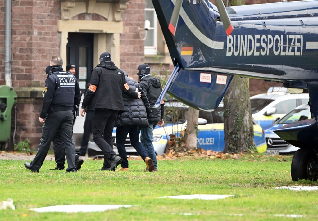 Beim Bundesgerichtshof in Karlsruhe wird eine Person von Polizisten aus einem Hubschrauber gebracht.