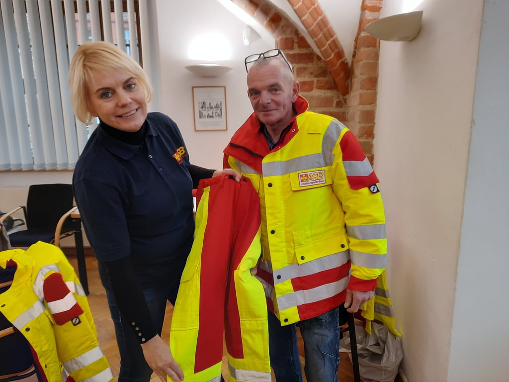 Nicole Bosold, Pressesprecherin des ASB, probiert mit Bewerber Michael Schrank aus Osterburg schonmal die neue Arbeitskleidung an.