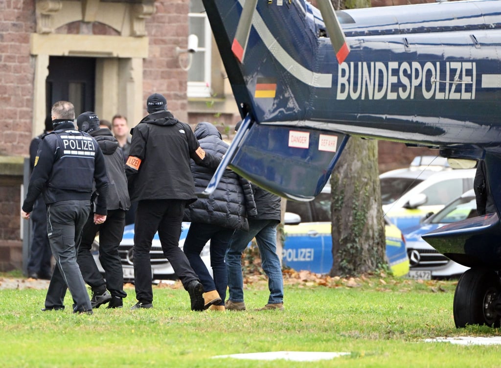 Eine Person (2.v.r.) wird von Polizisten aus einem Hubschrauber gebracht.
