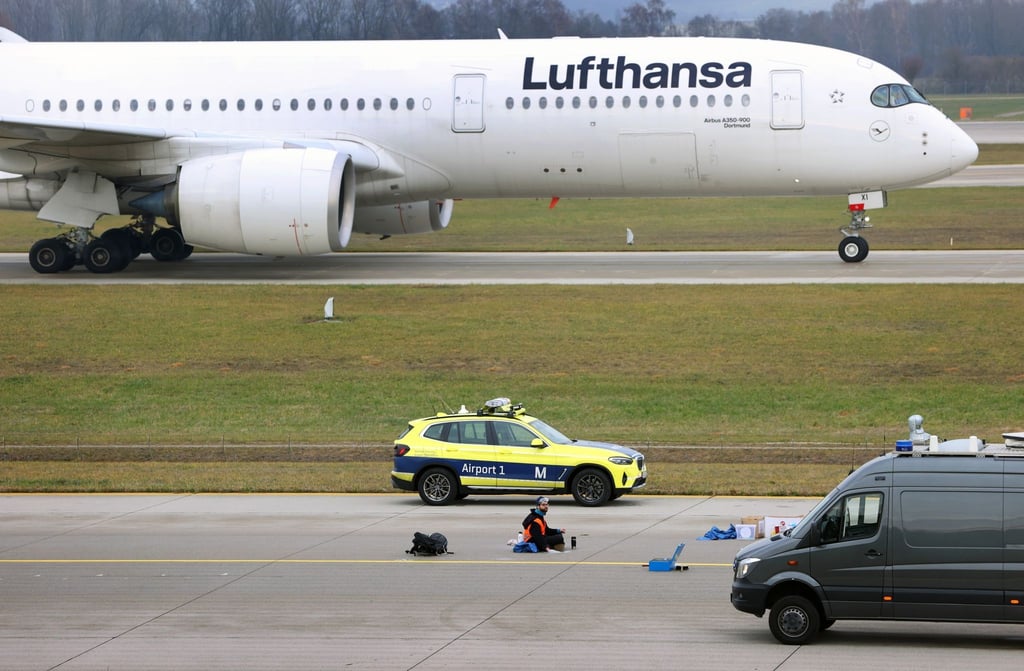 Ein Klimaaktivist sitzt mit angeklebter Hand auf dem Start-und Landebahn am Airport Franz-Josef-Strauß in München.
