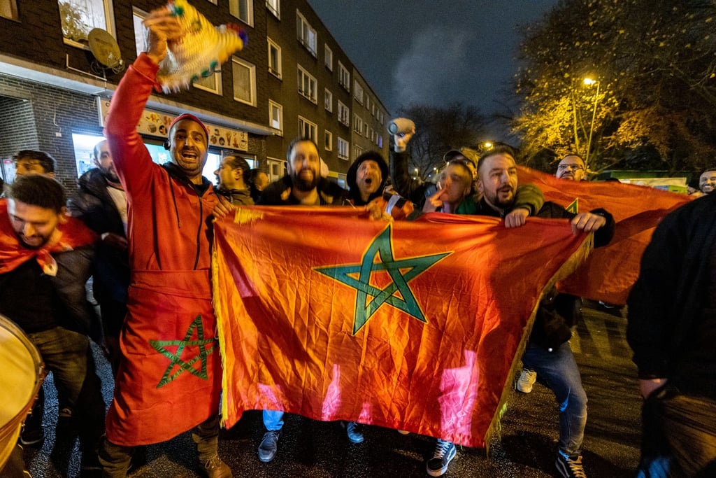 Marokko-Fans feiern auf der Straße mit Flaggen und Trommeln nach dem Sieg ihrer Mannschaft im Elfmeterschießen.