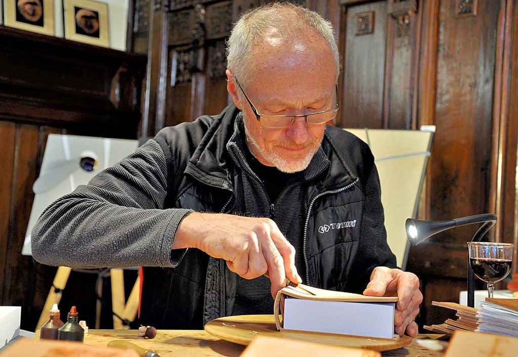 Miroslav Novotny verziert Ledereinbände für Notizbücher auf dem Kunsthandwerkermarkt im Rathaus in Stendal.