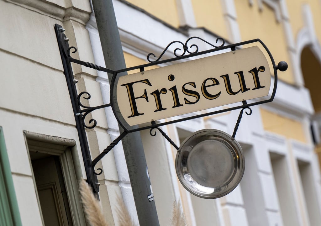 Ein Schild mit der Aufschrift „Friseur“ hängt über dem Eingang zu einem Friseursalon.