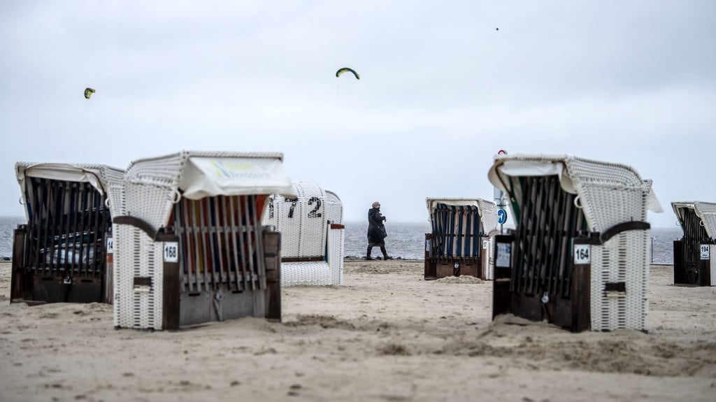 Spaziergänger laufen bei Regen über den Strand von Norddeich.