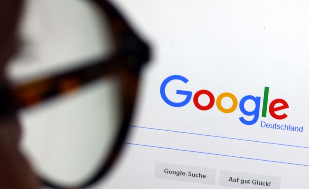 Die Seite der Suchmaschine von Google ist hinter einer Frau mit Brille zu sehen.