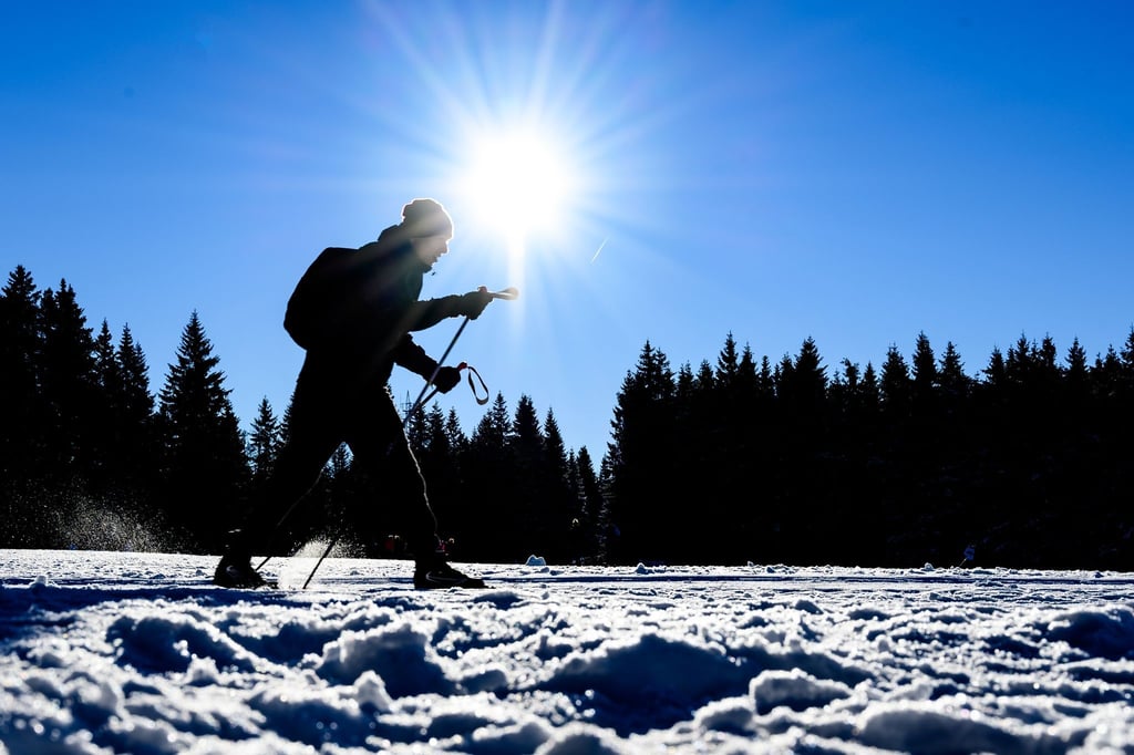 Ein Wintersportler auf Langlaufskiern fährt über eine Loipe.