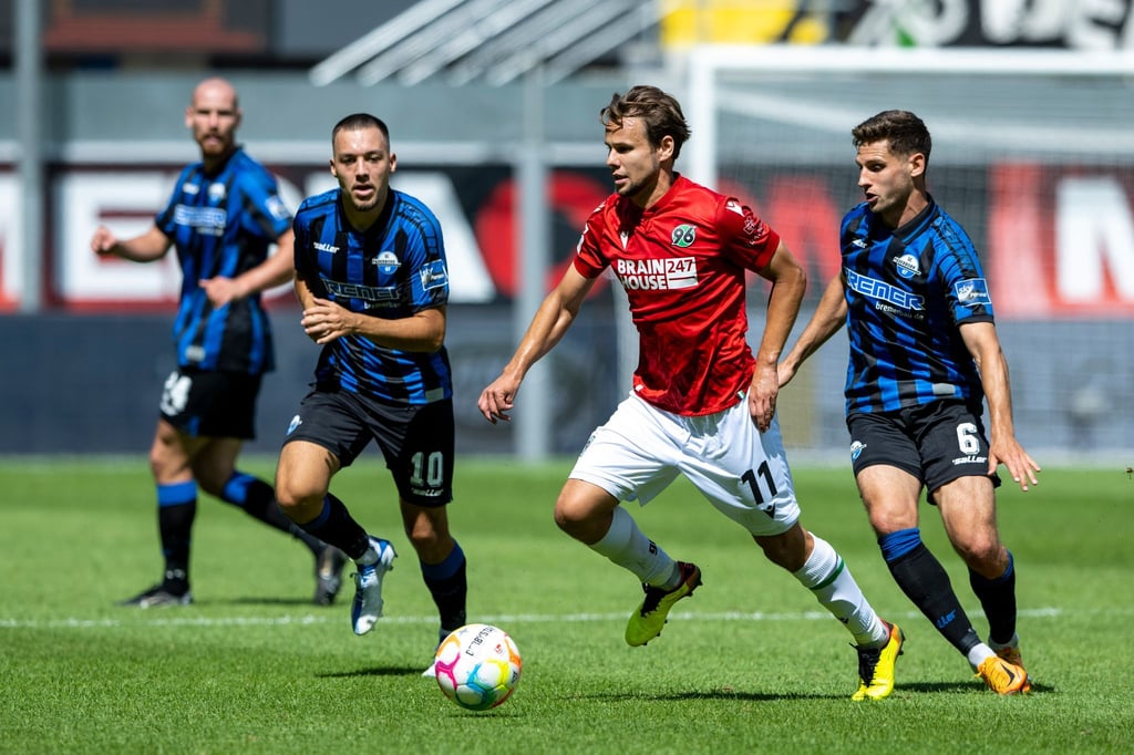Paderborns Julian Justvan (l-r), Hannovers Louis Schaub und Paderborns Marco Schuster kämpfen um den Ball.