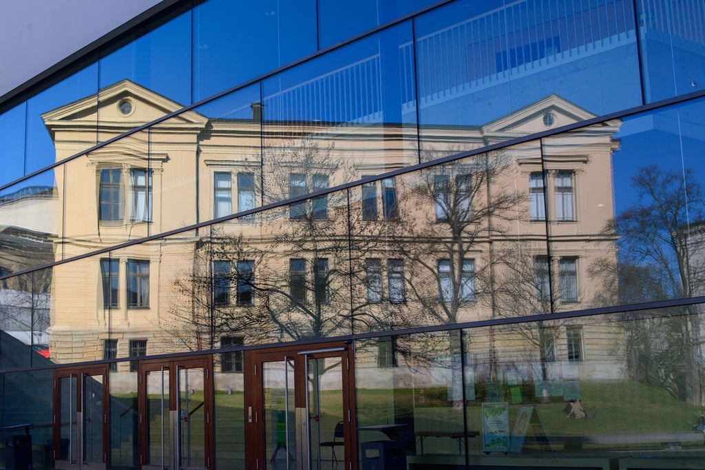 Ein Gebäude der Martin-Luther-Universität spiegeln sich in der Scheibe eines weiteren Uni-Gebäudes.