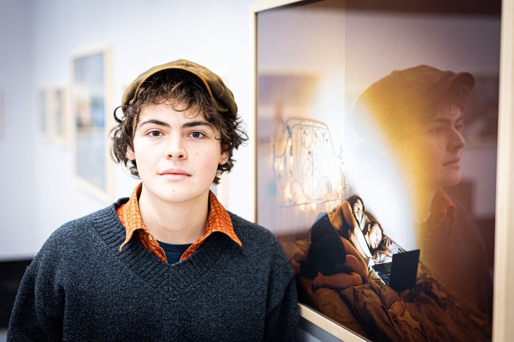 Fotograf Valentin Goppel steht neben einem seiner ausgestellten Fotos in der Galerie für Fotografie.