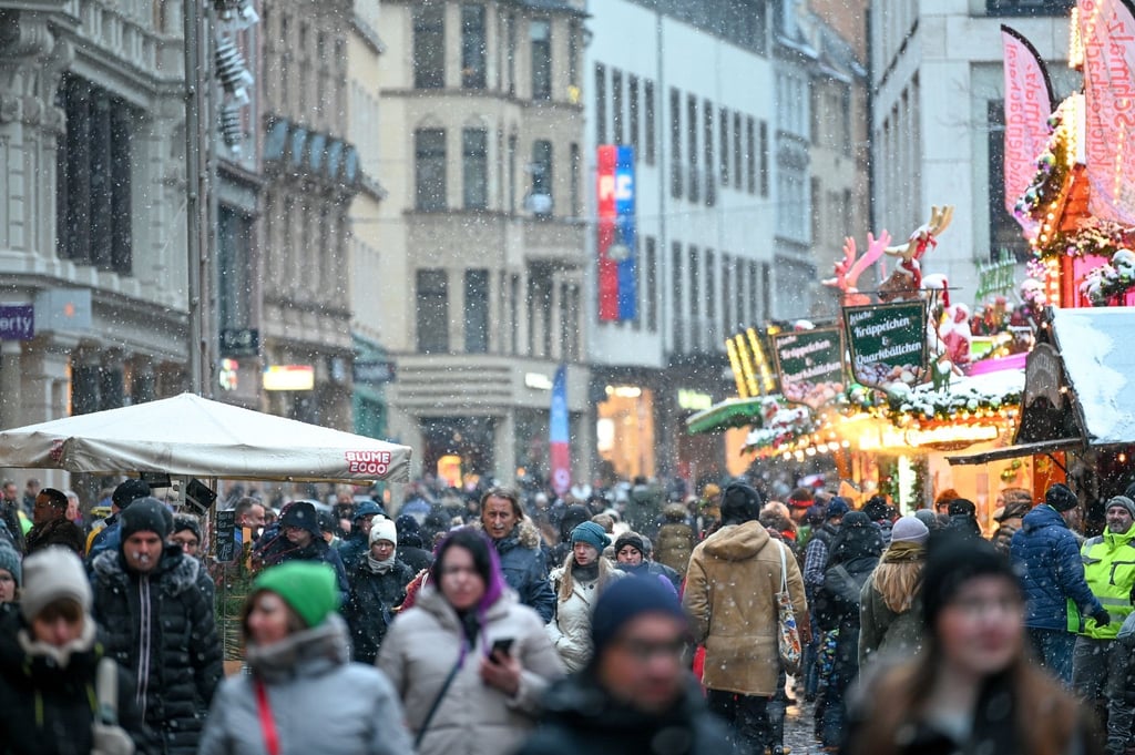 Passanten gehen in der Innenstadt von Halle über die Leipziger Straße.