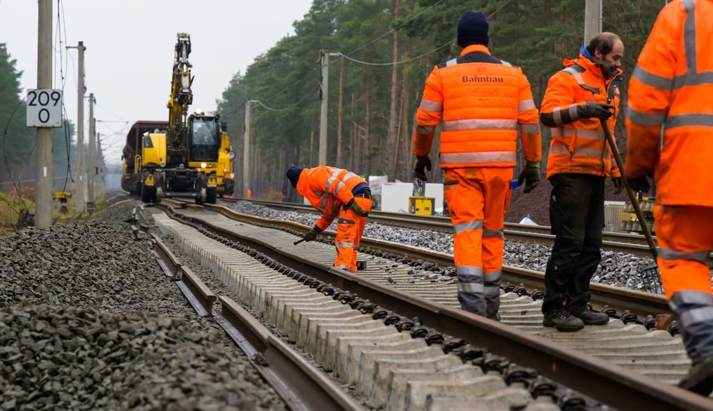 Mitarbeiter der Deutschen Bahn verlegen neue Schienen an der Unfallstelle.