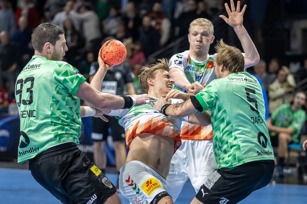 Gisli Kristjansson von SC Magdeburg wird festgemacht von Berlins Mijajlo Marsenic (l) und Max Darj (r).