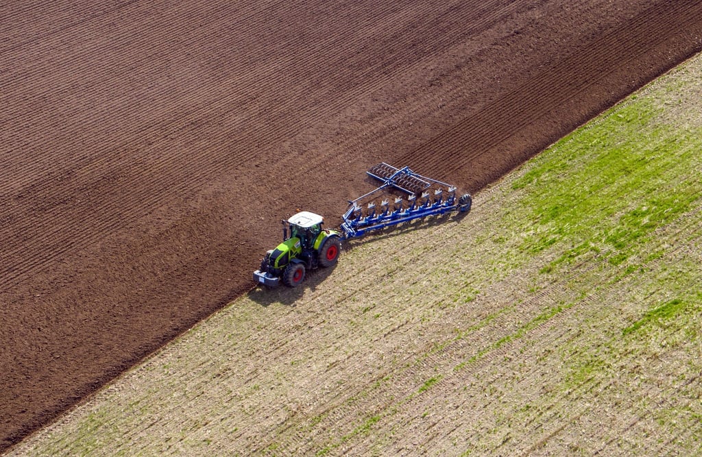 Ein Landwirt pflügt ein abgeerntetes Feld und bereitet es für die Neubestellung vor.