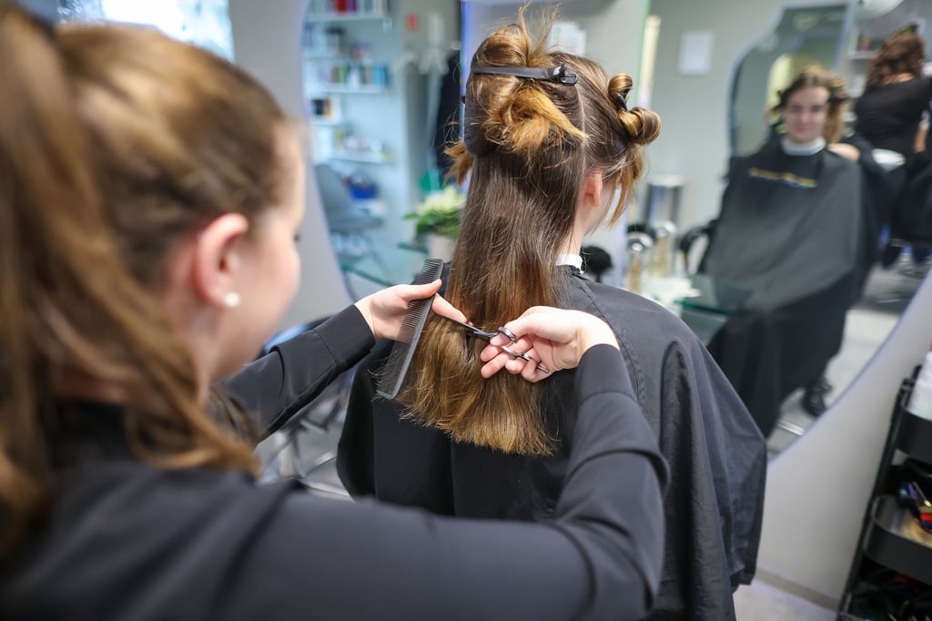 Eine Friseurmeisterin schneidet in einem Salon einer Kundin die Haare.