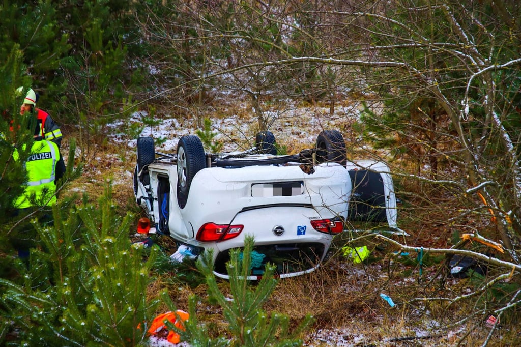 Ein Auto liegt neben der Autobahn auf dem Dach.