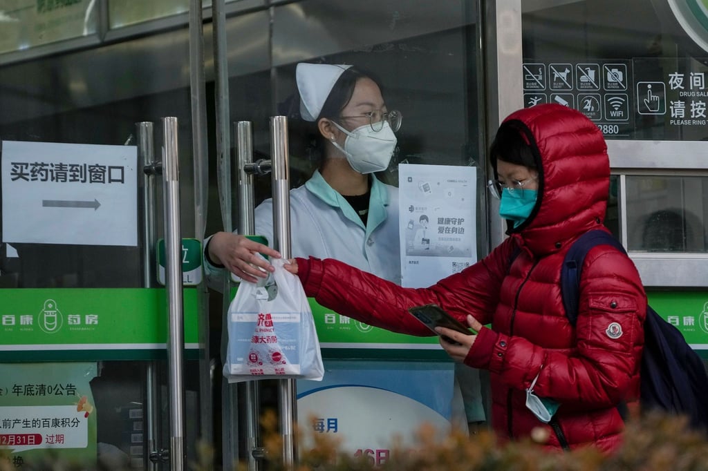 Eine Frau holt in einer Apotheke in Peking Covid-19-Antigen-Kits ab.