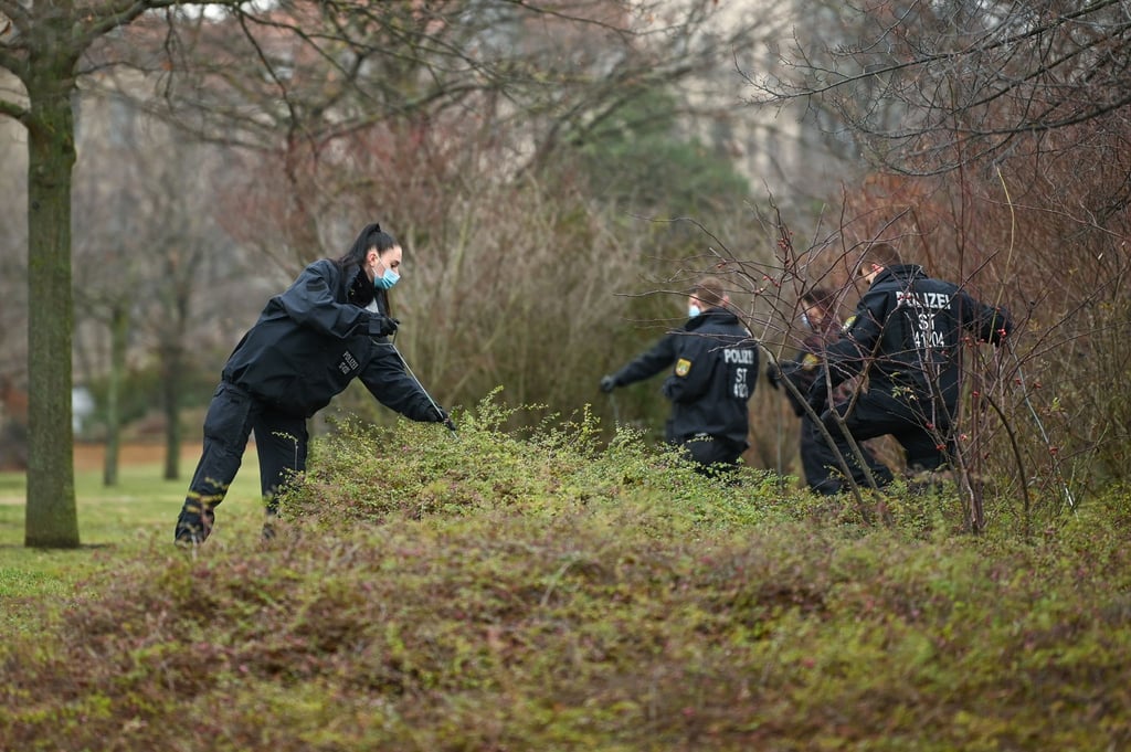 Eine Polizistin durchsucht zusammen mit Kollegen ein Gebüsch.