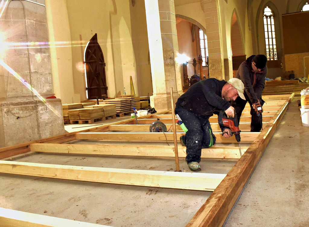 Marco Kränert und Steffen Siewert von einer Tischlerfirma aus Heldrungen bereiten den Wiedereinbau der Kirchenbänke vor.