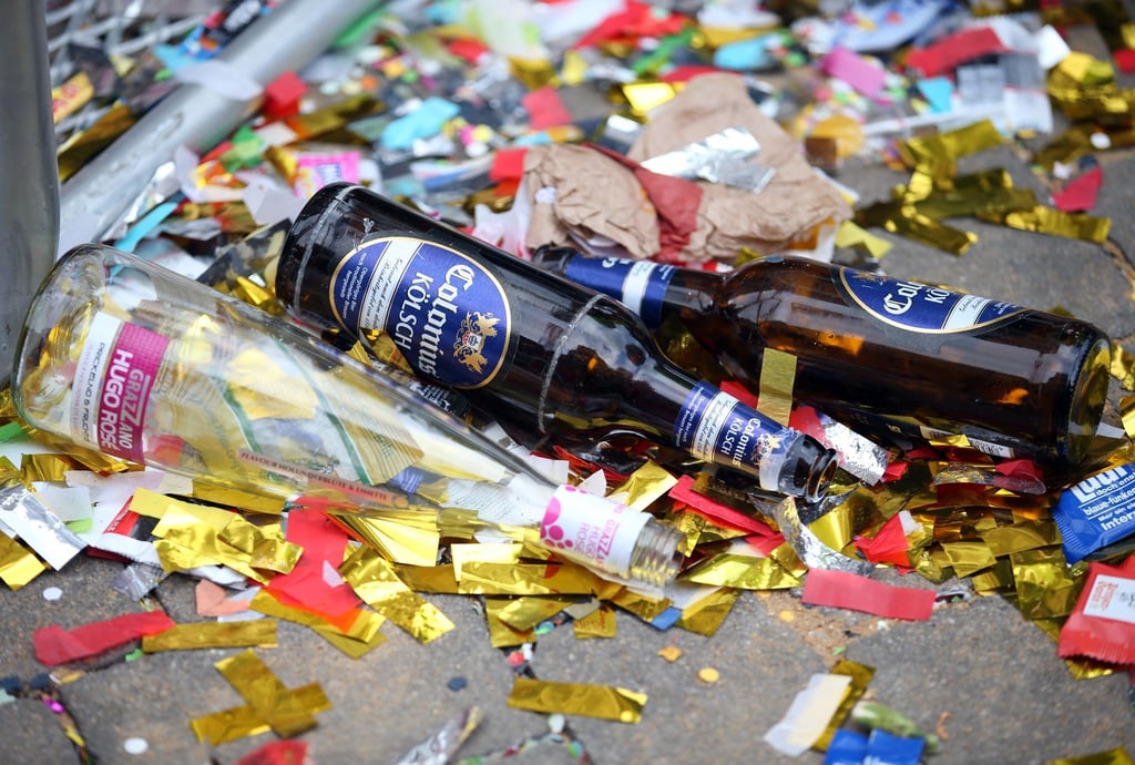 Leere Bierflaschen liegen zwischen Müll und Konfetti auf der Straße.