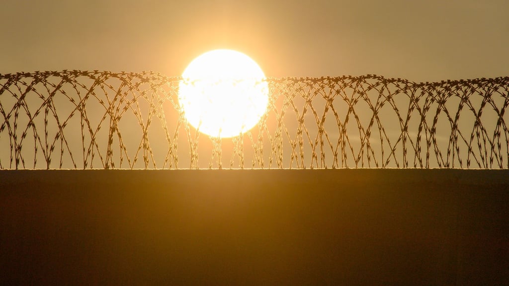 Die Sonne geht über der drahtbewährten Mauer der Justizvollzugasanstalt Burg auf.