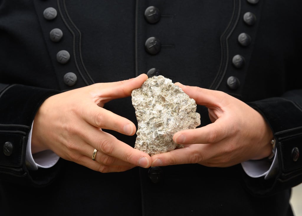 Der sächsische Wirtschaftsminister hält ein mit Lithium durchsetztes Stück Erz in den Händen.