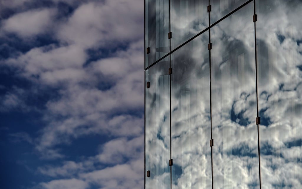 Wolken spiegeln sich in einer Glasfassade.