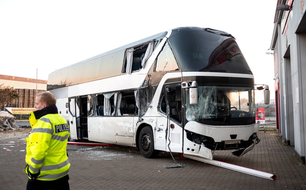 Ein beschädigter Reisebus steht nach einem Unfall auf einem Parkplatz.