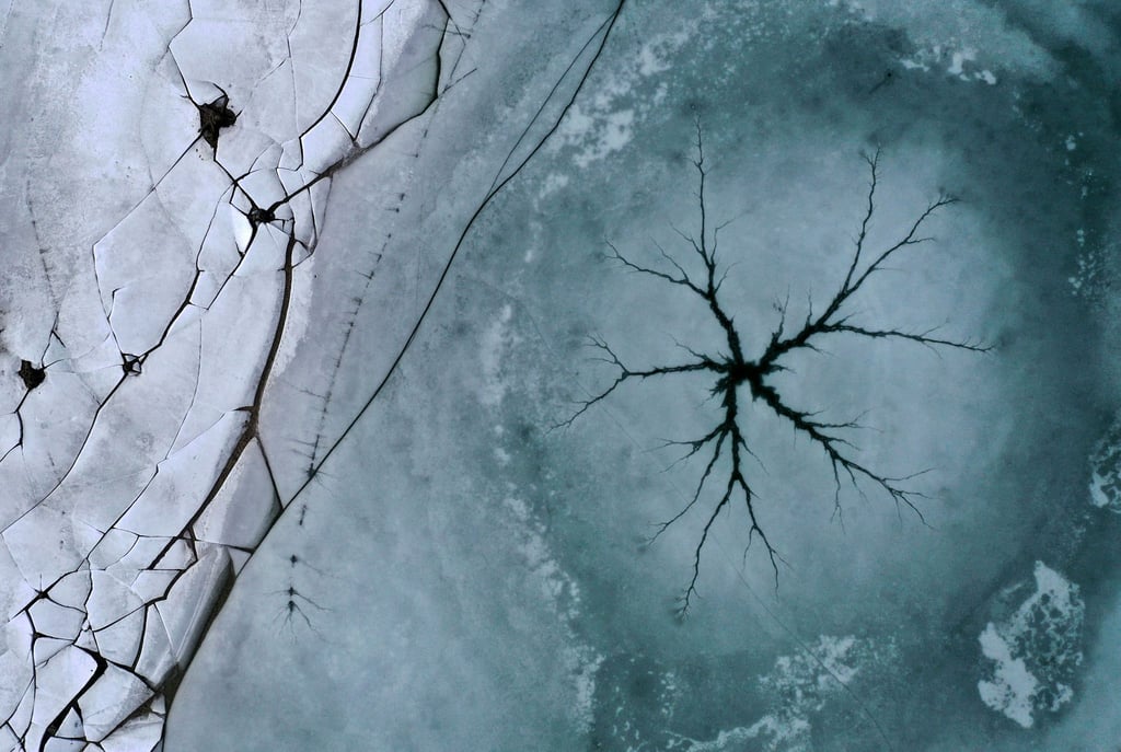 Ein sternförmiger Riss ist auf der Eisfläche eines Sees zu sehen.