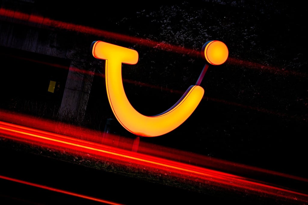 Ein Logo der Tui AG leuchtet am Morgen vor einem Gebäude der Konzernzentrale.