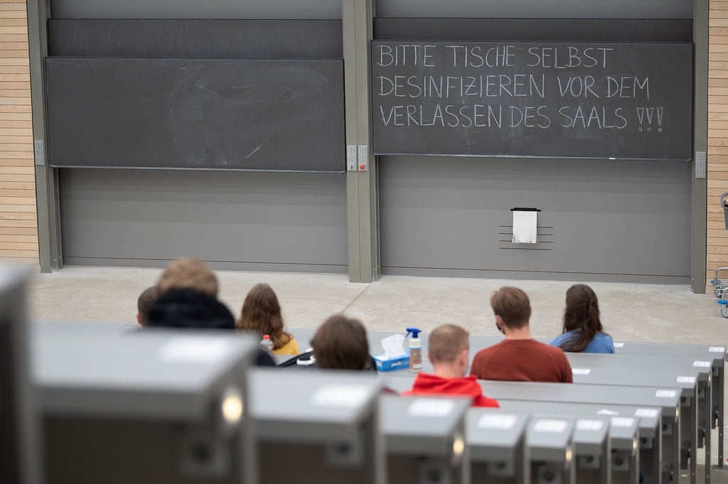 Studierende mit Mund- und Nasenmaske sitzen in einem Hörsaal.