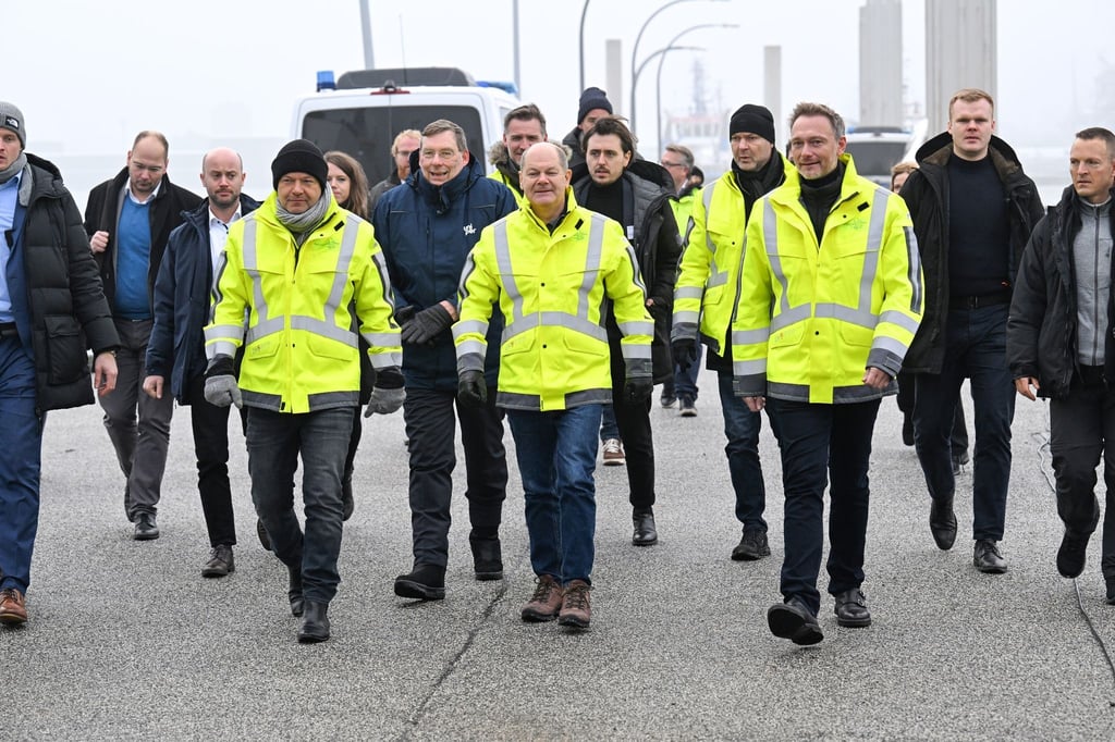 Robert Habeck (Bündnis 90/Die Grünen, r-l), Bundeskanzler Olaf Scholz (SPD) und Christian Lindner (FDP) laufen auf einem Pier.