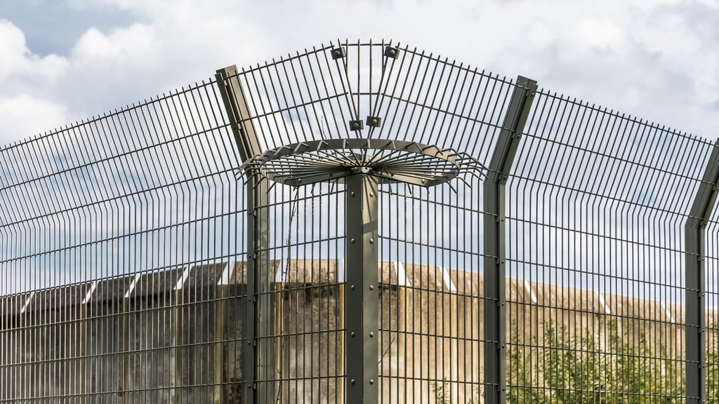 Eine Mauer und ein Drahtzaun eines Gefängnisses.