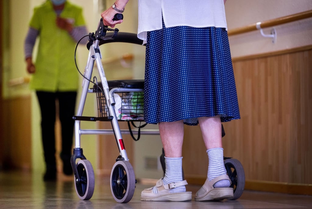 Eine ältere Dame geht mit ihrem Rollator über einen Flur.