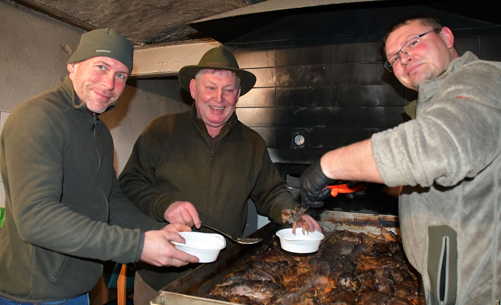 Christian Mettner (v.l.), Franz Maier und David Schulz haben einen Festtagsbraten aus dem Backofen geholt und für die Gäste portioniert.