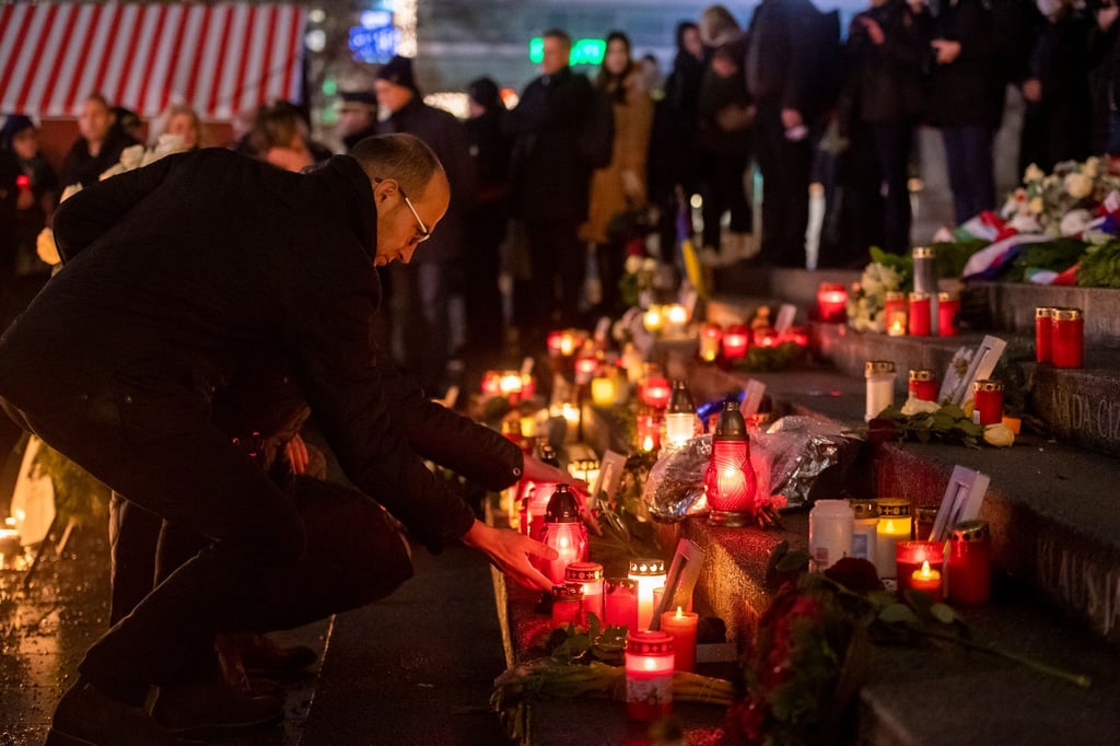 Menschen zünden bei der Gedenkveranstaltung zum Terroranschlag auf dem Berliner Breitscheidplatz an der Gedächtniskirche Kerzen an.