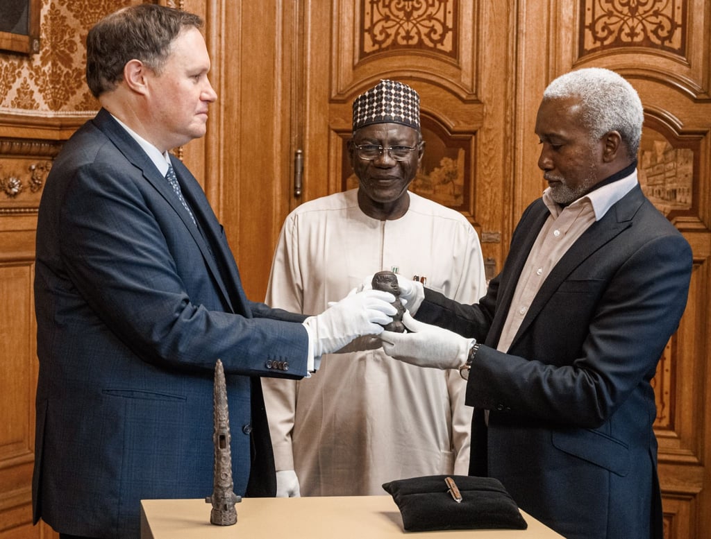 Kultursenator Carsden Brosda (SPD, l-r), der Generaldirektor der Nationalen Behörde für Museen und Denkmäler in Nigeria Abba Isa Tijani und Botschafter Yusuf Matama Tuggur vollziehen eine symbolische Übergabe.