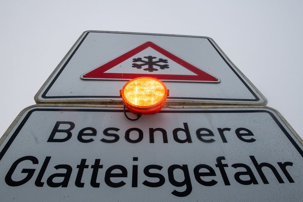 Ein Straßenschild warnt mit einer Blinkleuchte vor Glatteis.