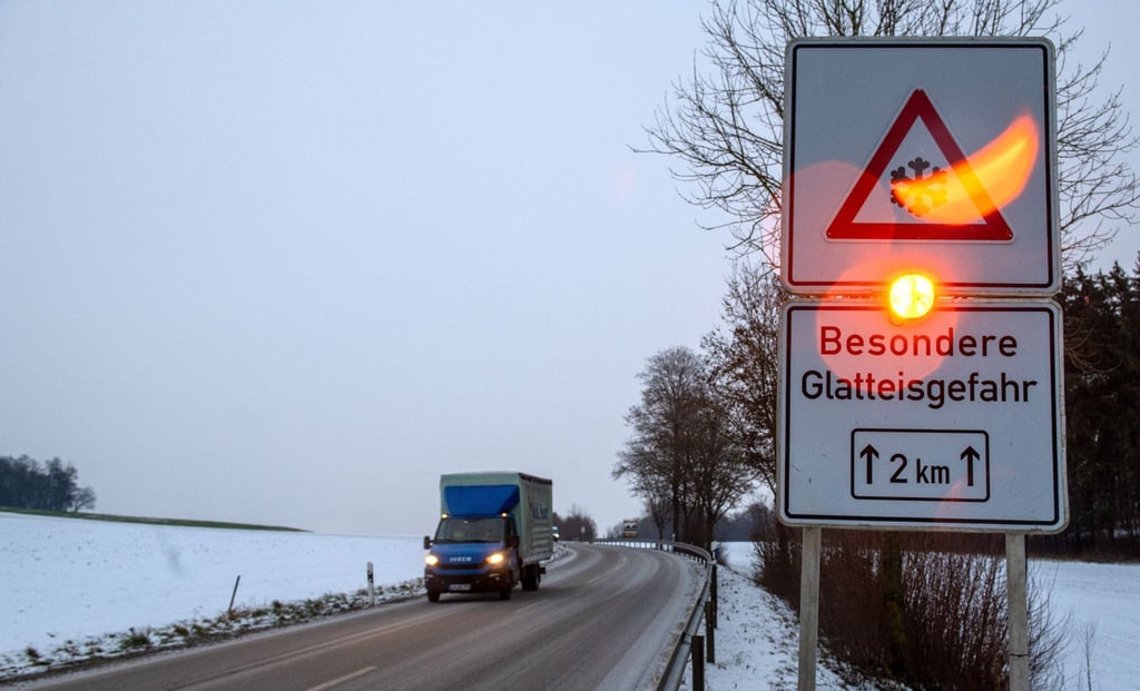 Ein Straßenschild warnt mit einer Blinkleuchte vor Glatteis.