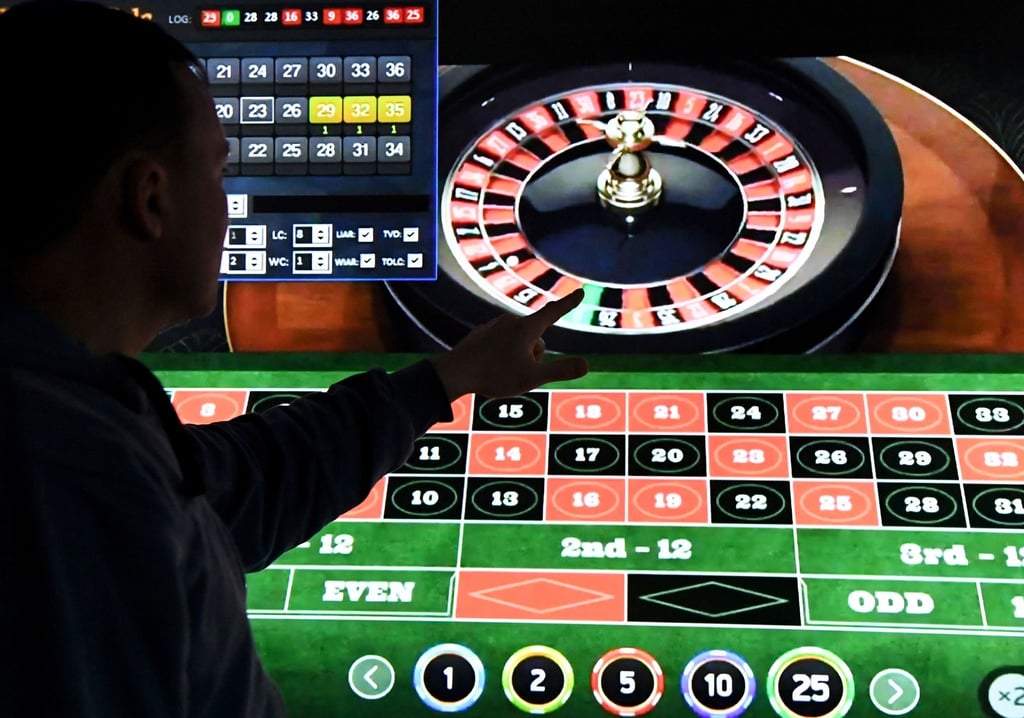 Ein Mann steht vor einem Bildschirm mit einer Seite für Online-Roulette.