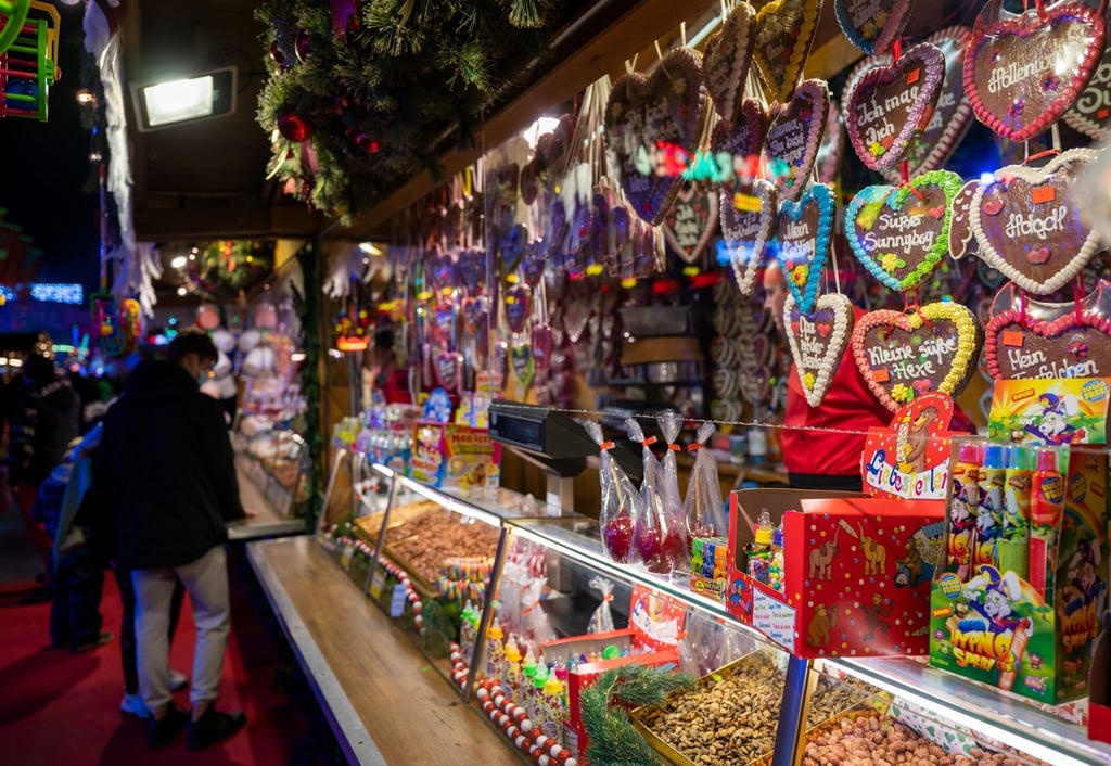 Ein Stand auf einem Weihnachtsmarkt bietet Süßigkeiten wie Lebkuchenherzen zum Verkauf an.