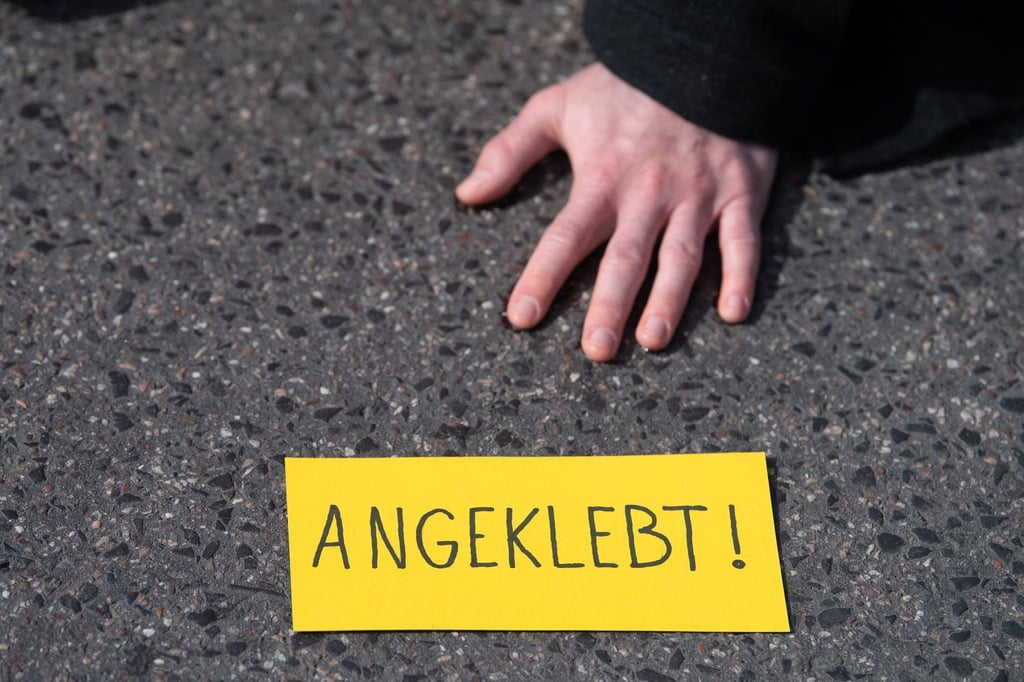 Ein Demonstrant ist bei einem Protest der Gruppe „Letzte Generation“ auf einer Straße festgeklebt.