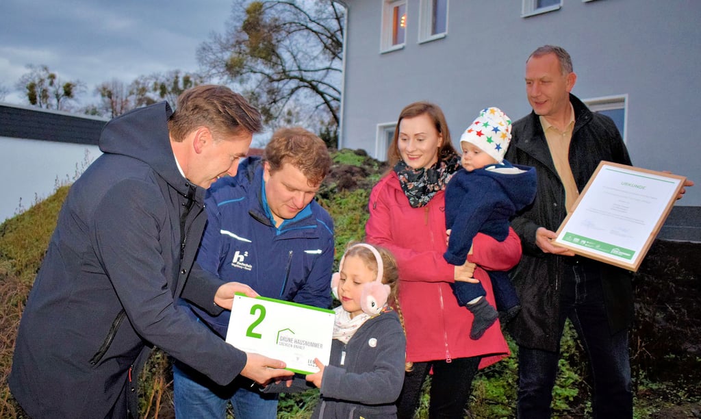 Emilia nahm stellvertretend für ihre Eltern Felix und Jennifer Steeger die Grüne Hausnummer aus den Händen von Staatssekretär Thomas Wünsch entgegen. Bürgermeister Jens Hünerbein (r.) durfte die dazugehörige Urkunde überreichen.