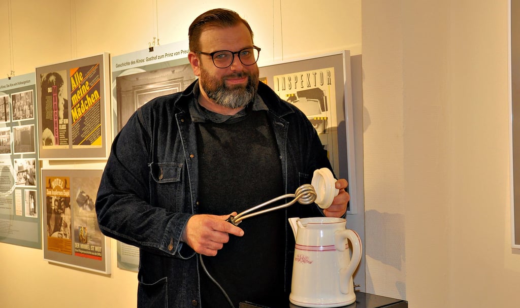 Museumsleiter Florian Fischer zeigt eine Kanne, die ursprünglich aus der Gastwirtschaft „Prinz von Preußen“ stammt. Die Kanne wurde später im Kino vom Filmvorführer und seinen Kollegen zum Aufbrühen des Kaffeewassers genutzt.