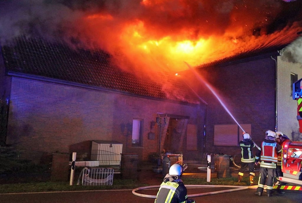 Feuerwehrleute löschen ein brennendes Dach.