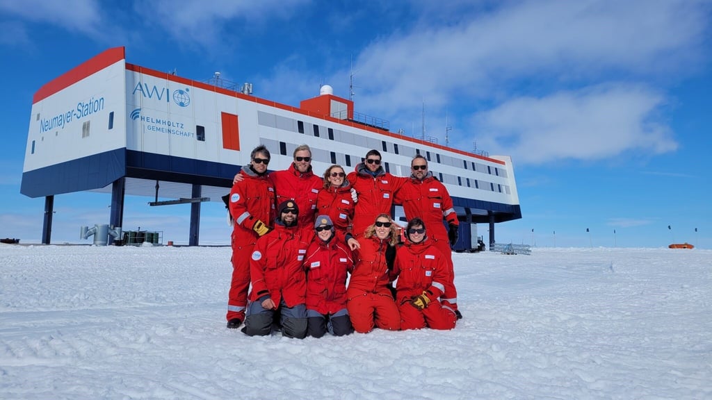 Das neunköpfige Überwinterungsteam posiert vor der Forschungsstation Neumayer III in der Antarktis.