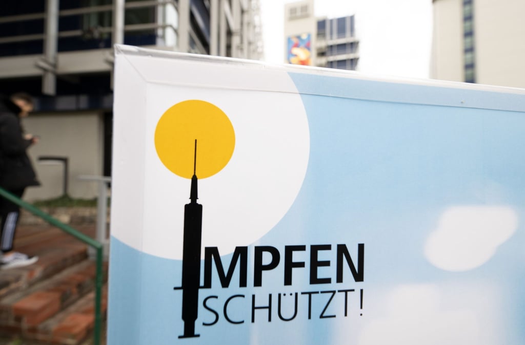 Ein Plakat mit der Aufschrift „Impfen schützt“ steht vor einem Impfzentrum.