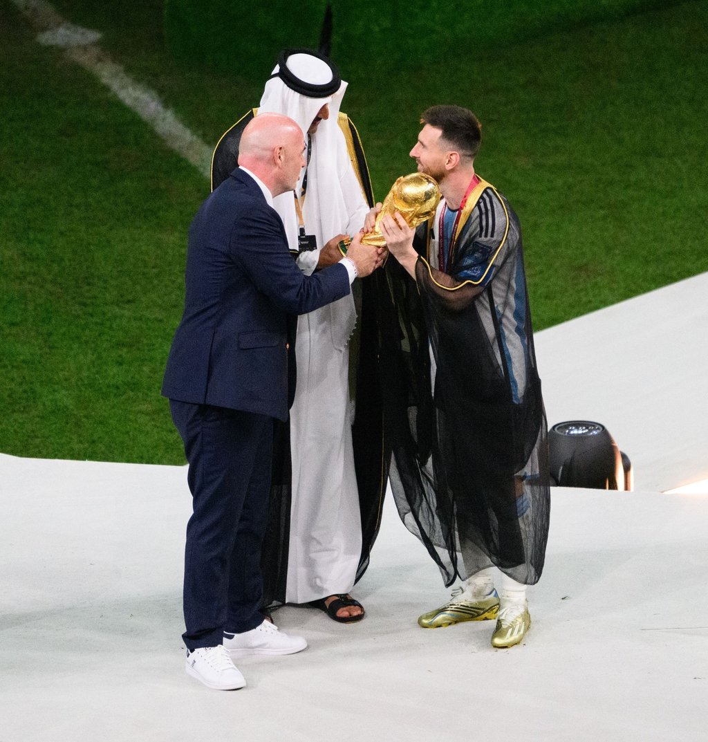 Historischer Moment: Scheich Tamim bin Hamad Al Thani (M) und FIFA-Boss Gianni Infantino (l) übergeben Argentiniens Lionel Messi den WM-Pokal.