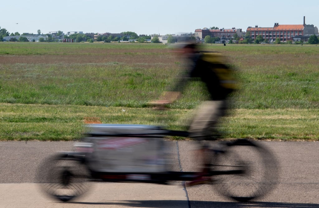 Ein Mann fährt beim sonnigen Wetter auf einem Lastenrad.